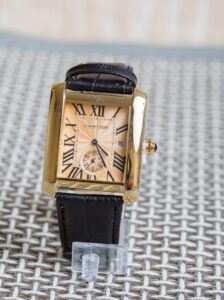 Gold Cartier tank watch with a black strap and gold details 